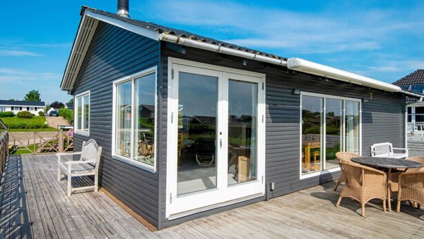 A modern house with a deck, large sliding glass doors, and a chimney. - 5 Person Holiday Home in Hejls (Hejls)