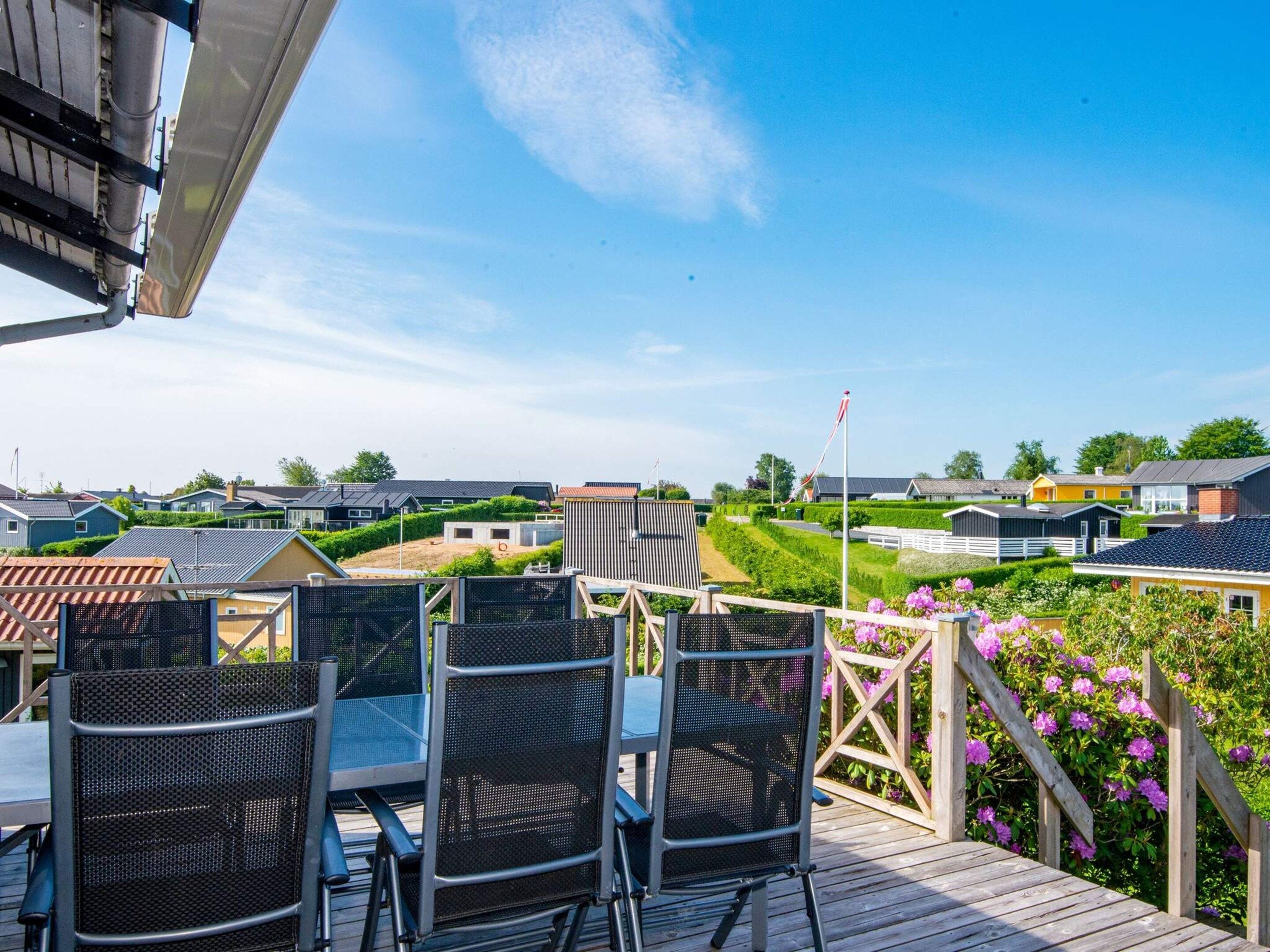 A deck with outdoor seating, overlooking a residential area with houses and a well-maintained garden.