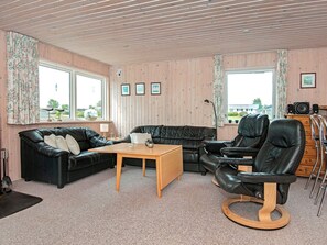 A room with a black leather sofa, a wooden coffee table, a black leather chair, and a wooden cabinet. - 5 Person Holiday Home in Hejls (Hejls)