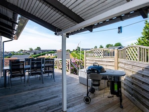 Un patio al aire libre con una parrilla, sillas y una mesa.