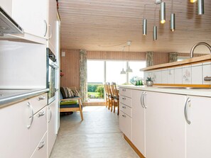A kitchen with a dining area, wooden ceiling, and a view of the outdoors.