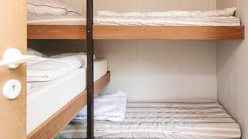 A bunk bed room with wooden frames and white bedding.