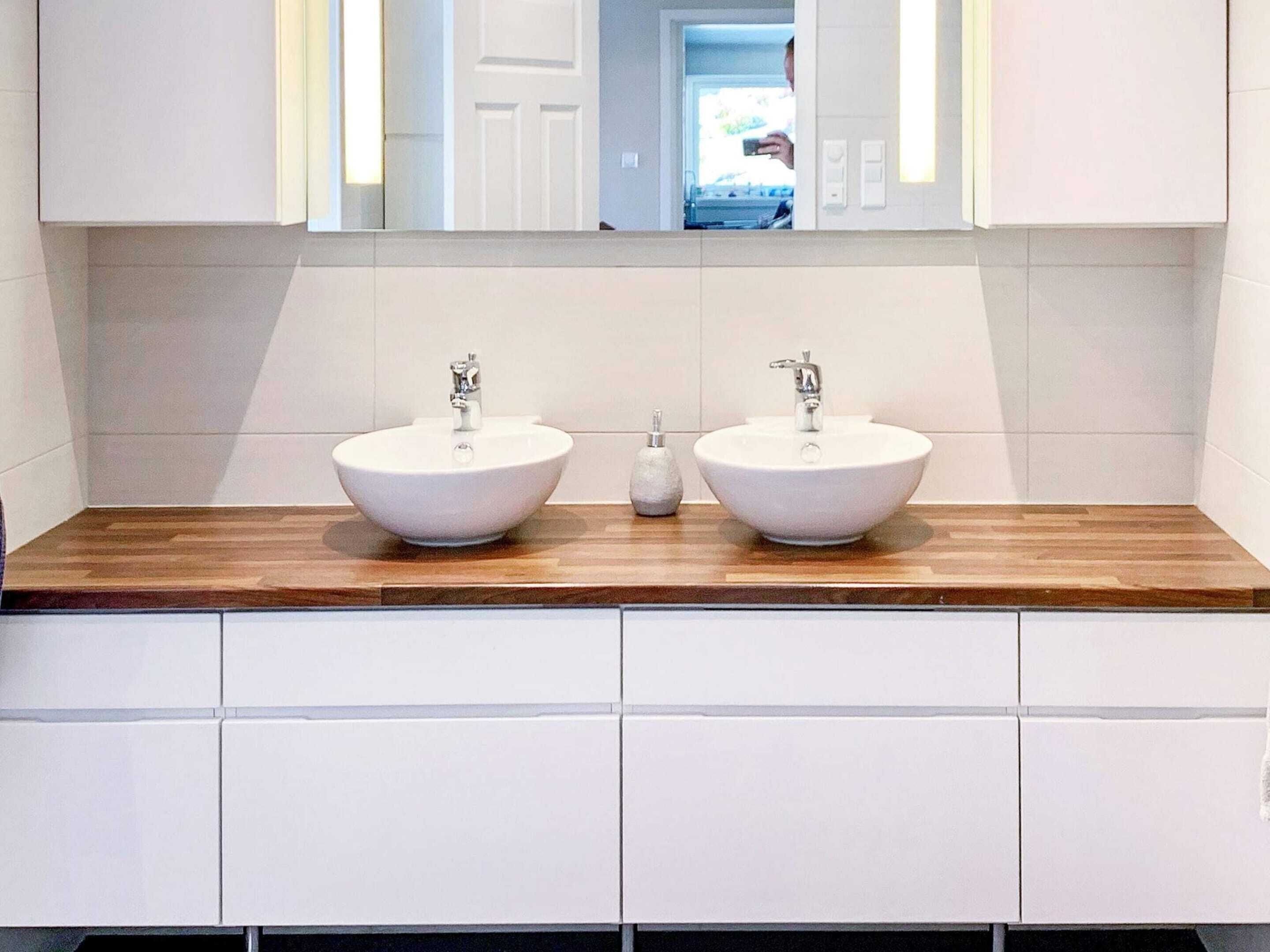 A bathroom with two white sinks, a wooden countertop, and a mirror above.