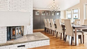 A modern dining area with a fireplace, wooden flooring, and a chandelier.