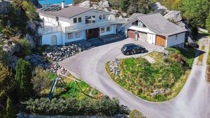 A two-story house with a garage, driveway, and a view of the sea.