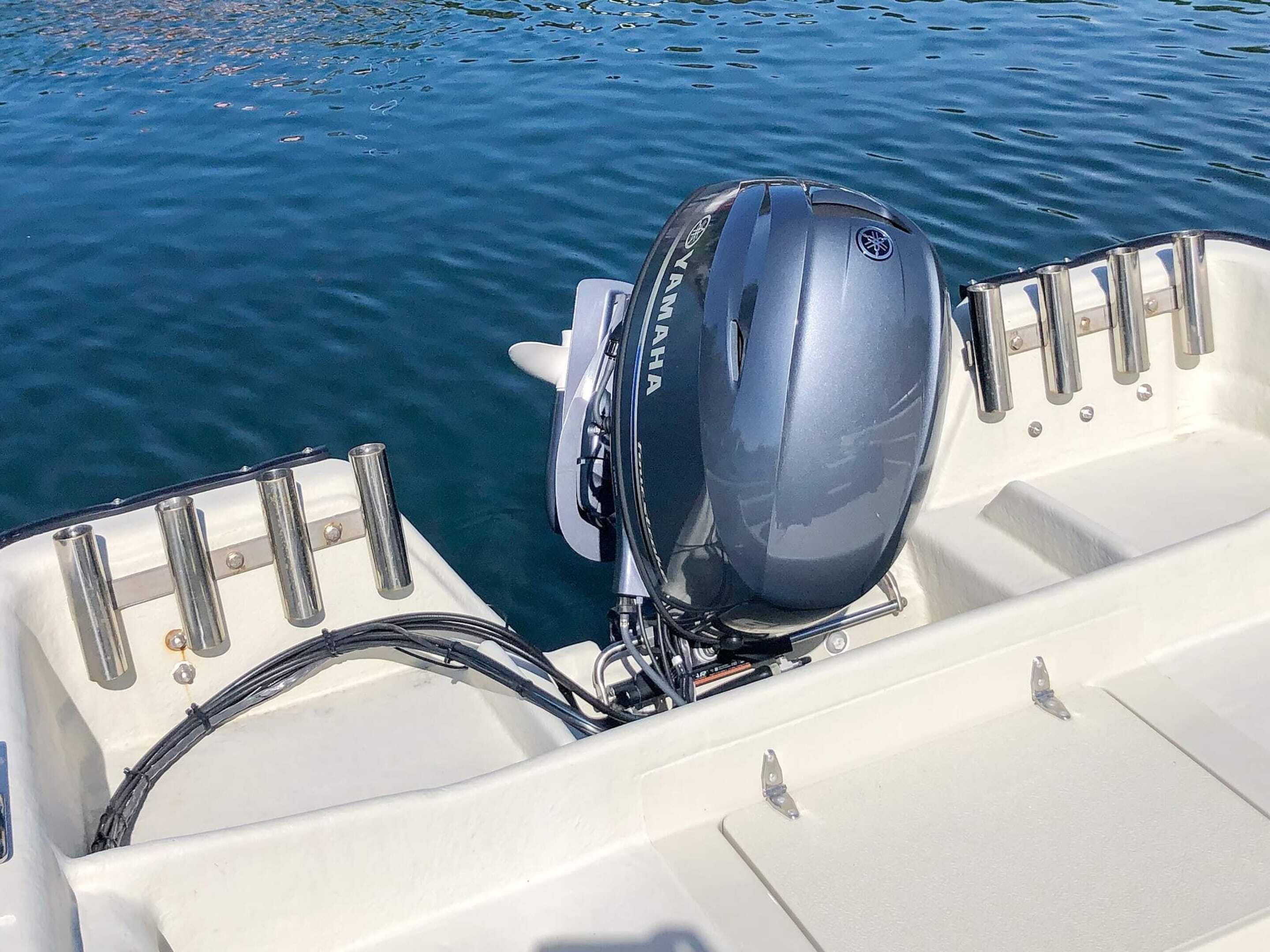 La partie arrière d’un bateau, équipée d’un moteur hors-bord Yamaha, de barrières métalliques et d’une coque blanche.
