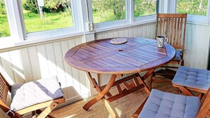 A wooden table and chairs with cushions, a coffee mug, and a window with a view of greenery. - 5 Person Holiday Home in Storvik (Storvik)