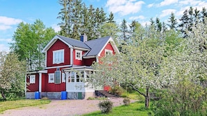 A red two-story house with a porch and a gravel driveway. - 5 Person Holiday Home in Storvik (Storvik)