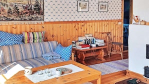 A cozy living room with a wooden sofa, a coffee table, and a bookshelf. - 5 Person Holiday Home in Storvik (Storvik)