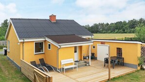 A yellow house with a wooden deck, a covered patio, and a small outdoor seating area. - Holiday Home in LÃ¦sÃ¸ (Læsø)