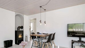 A modern living room with a fireplace, dining table, and TV. - Holiday Home in LÃ¦sÃ¸ (Læsø)