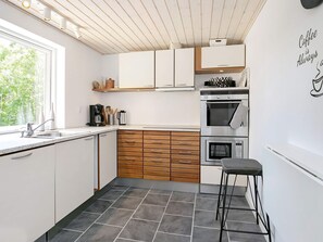 A modern kitchen with white cabinets, a wooden countertop, and a bar stool. - Holiday Home in LÃ¦sÃ¸ (Læsø)