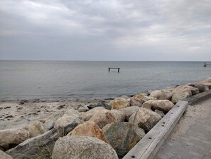 A rocky shoreline with a wooden walkway leading to the sea.
