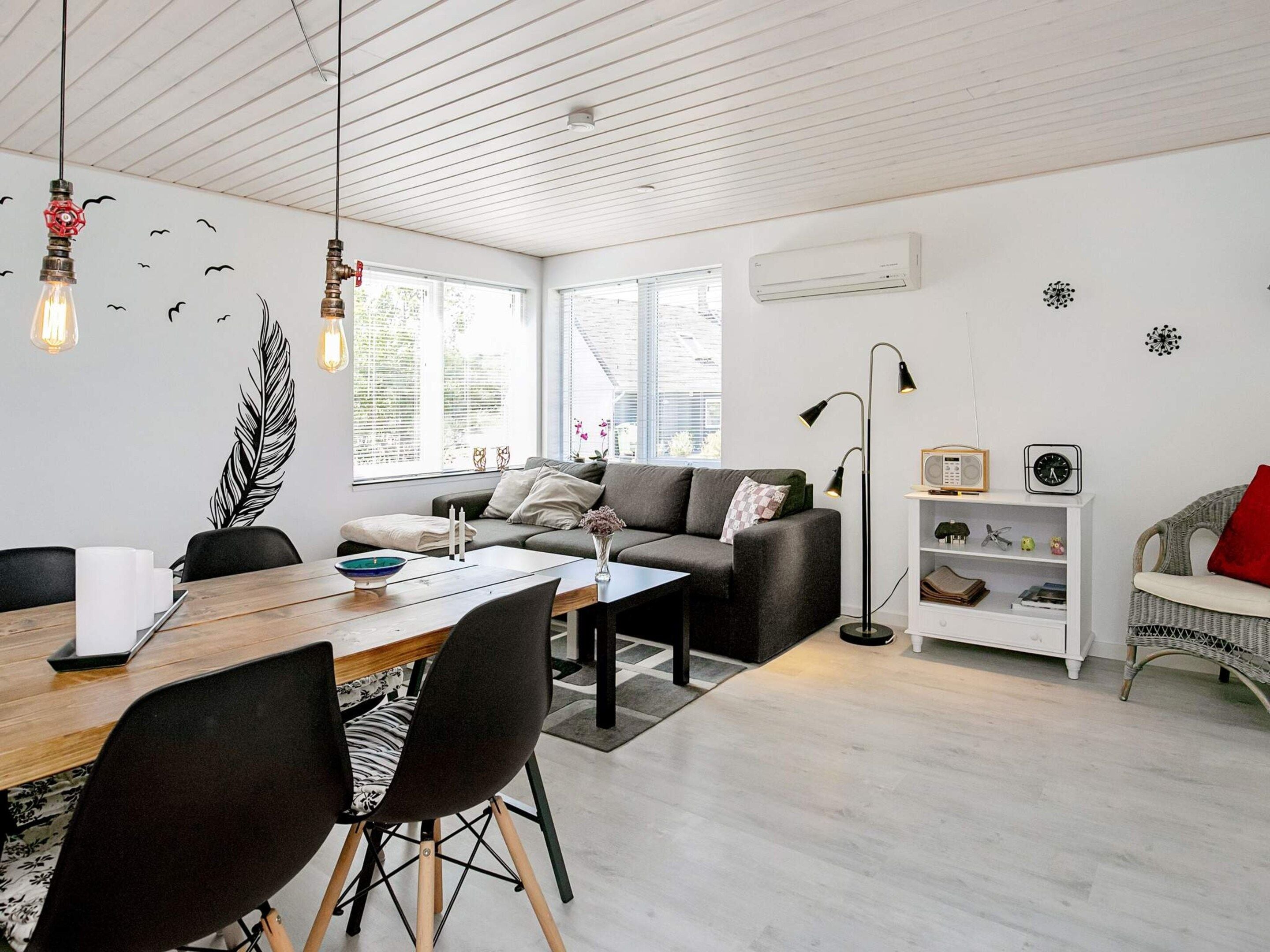 A modern living room with a dining area, featuring a sofa, a table, and chairs.