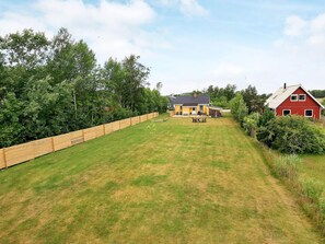 A residential property with a fenced backyard, a yellow house, and a red barn. - Holiday Home in LÃ¦sÃ¸ (Læsø)