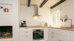 Eine moderne Küche mit weißen Schränken, einem eingebauten Backofen, einer Kaffeemaschine und einem Wandregal für Messer.