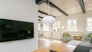 Ein modernes Wohnzimmer mit Couch, Fernseher an der Wand und Couchtisch aus Holz.