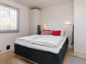 A bedroom with a bed, a window, and a wall-mounted light fixture. - 4 Person Holiday Home in Vejby (Vejby)