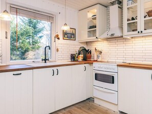 A kitchen with white cabinetry, a wooden countertop, a sink, a stove, and a window with blinds.
