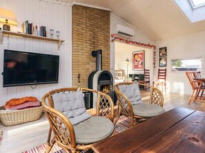 A cozy living room with a brick fireplace, wicker furniture, and a flat-screen TV.