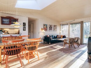 A spacious living area with a dining set, a sofa, and a coffee table. There is a kitchen area with a stove and cabinets. - 4 Person Holiday Home in Vejby (Vejby)