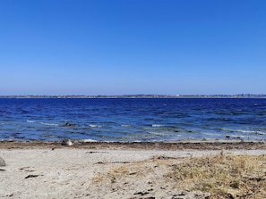 A coastal view with a clear sky, sandy beach, and a distant shoreline. - 4 Person Holiday Home in Skibby (Skibby)
