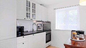 Eine moderne Küche mit weißen Schränken, einer schwarzen Arbeitsplatte und einem Fenster mit Aussicht.
