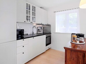 A modern kitchen with white cabinetry, a black countertop, and a window with a view. - 4 Person Holiday Home in Skibby (Skibby)