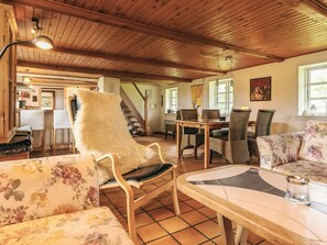 A cozy interior with a wooden ceiling, a dining area with wicker furniture, and a staircase leading to another level. - 4 Star Holiday Home in Rudkobing (Rudkobing)