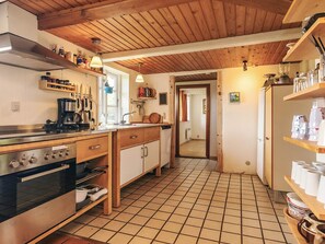 A kitchen with wooden cabinets, a stove, and a coffee maker. - 4 Star Holiday Home in Rudkobing (Rudkobing)