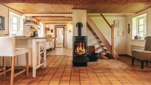 Een rustiek interieur met een betegelde vloer, houten balken, een keukenhoek en een trap.