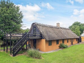 A traditional thatched-roof house with a wooden staircase leading to a balcony. - 4 Star Holiday Home in Rudkobing (Rudkobing)