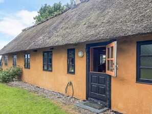 A single-story building with a thatched roof and a black door. - 4 Star Holiday Home in Rudkobing (Rudkobing)