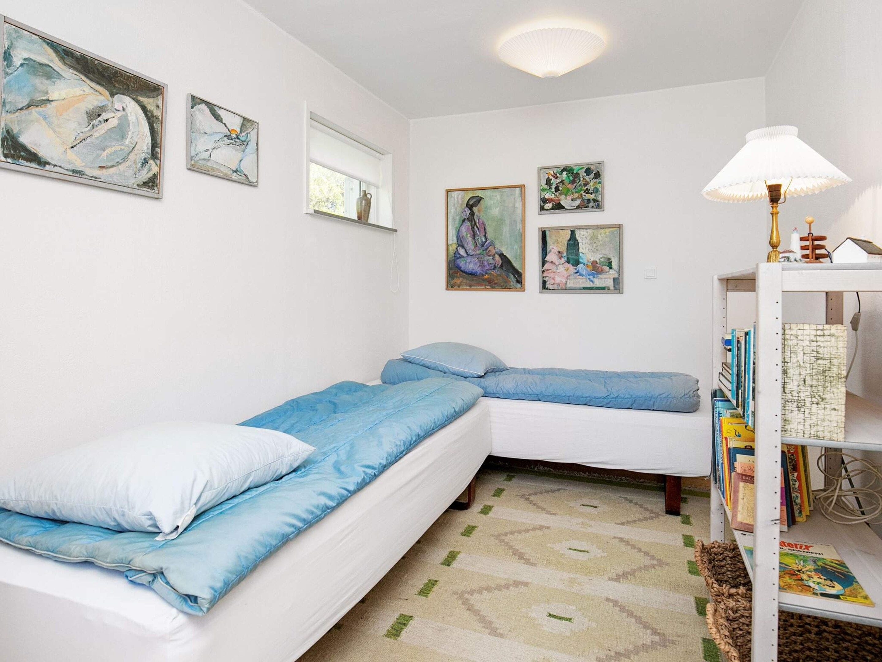 A room with a bed, a bookshelf, and wall art.