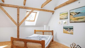 Un dormitorio con cama de madera, tragaluz y obras de arte en las paredes.