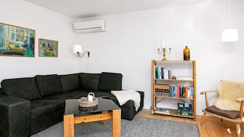 Una sala de estar moderna con un sofá seccional, una mesa de centro de madera, una estantería y una butaca decorativa.