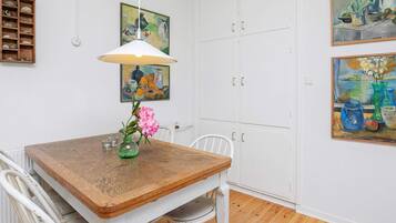 A dining area with a wooden table, white chairs, a hanging lamp, and artwork on the walls.