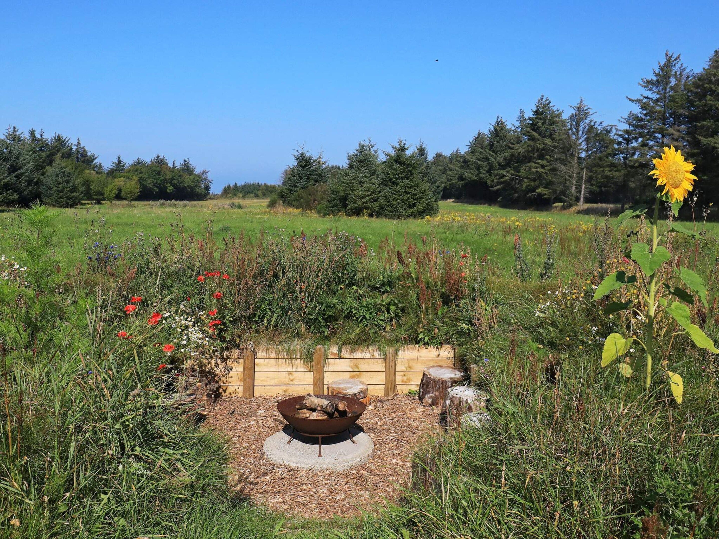 A garden with a fire pit surrounded by various plants and flowers.