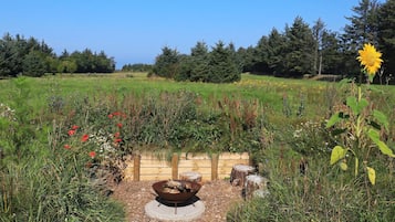 A garden with a fire pit surrounded by various plants and flowers.