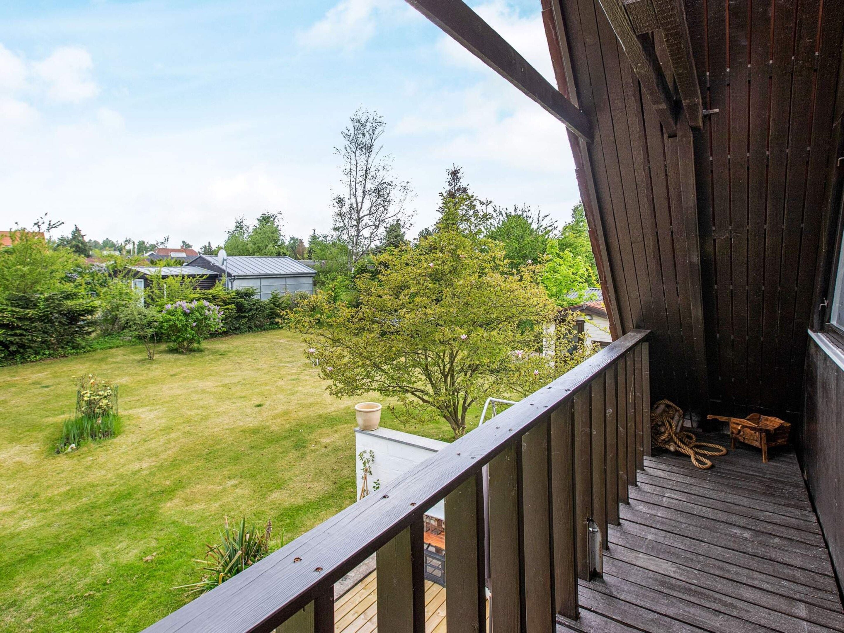 A wooden deck with a view of a grassy yard and a house in the background.
