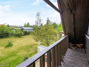 A wooden deck with a view of a grassy yard and a house in the background.