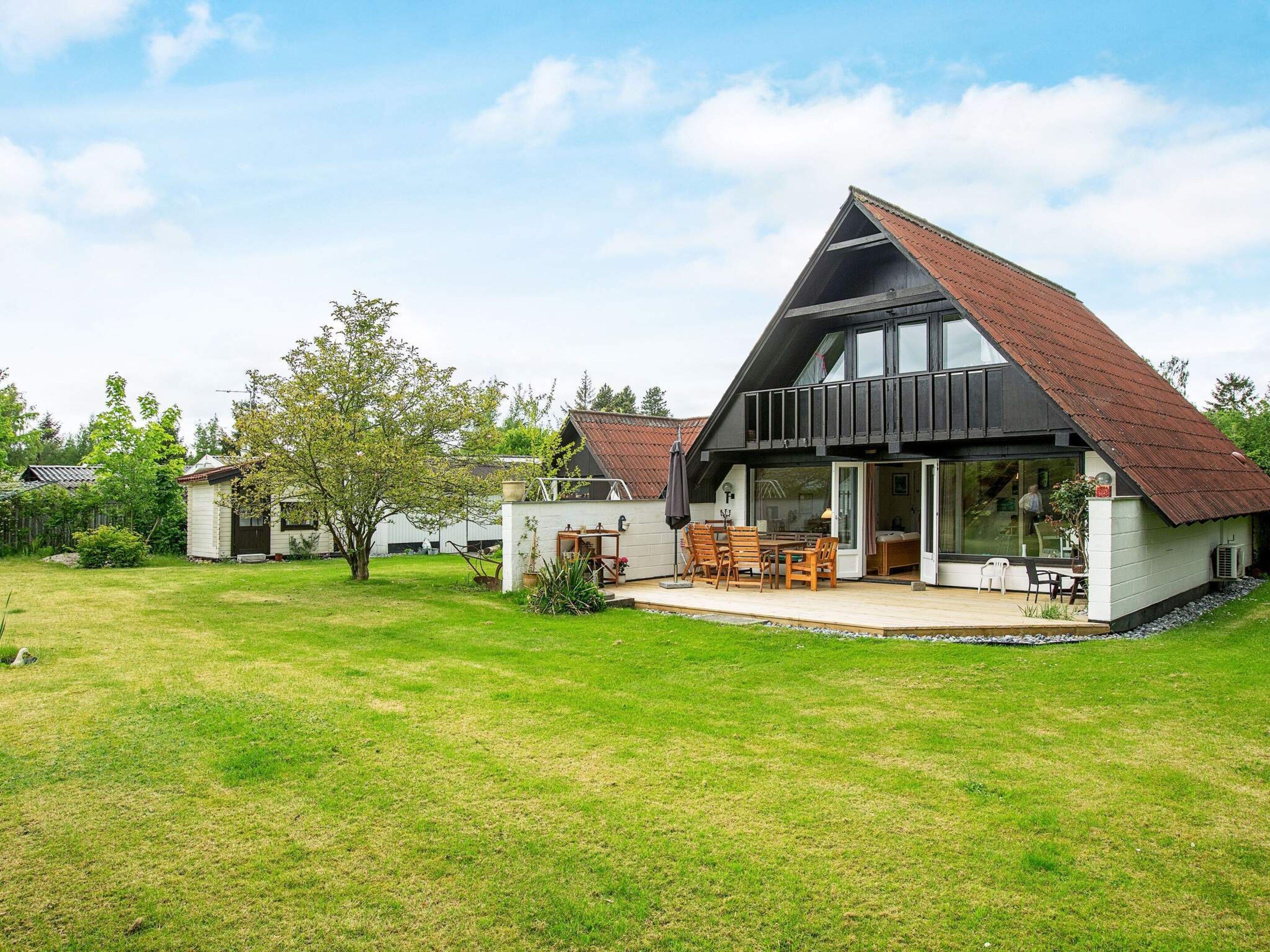 A modern house with a large patio, a dining area, and a covered outdoor seating area.