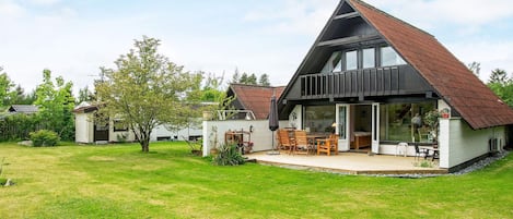 Une maison moderne dotée d’un grand patio, d’un coin repas et d’un espace extérieur aménagé et abrité.
