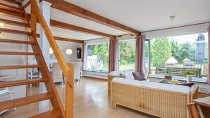A spacious living area with a wooden staircase, a wicker sofa, and a dining area with a table and chairs. - Holiday Home in VÃ¦ggerlÃ¸se (Vaeggerlose)
