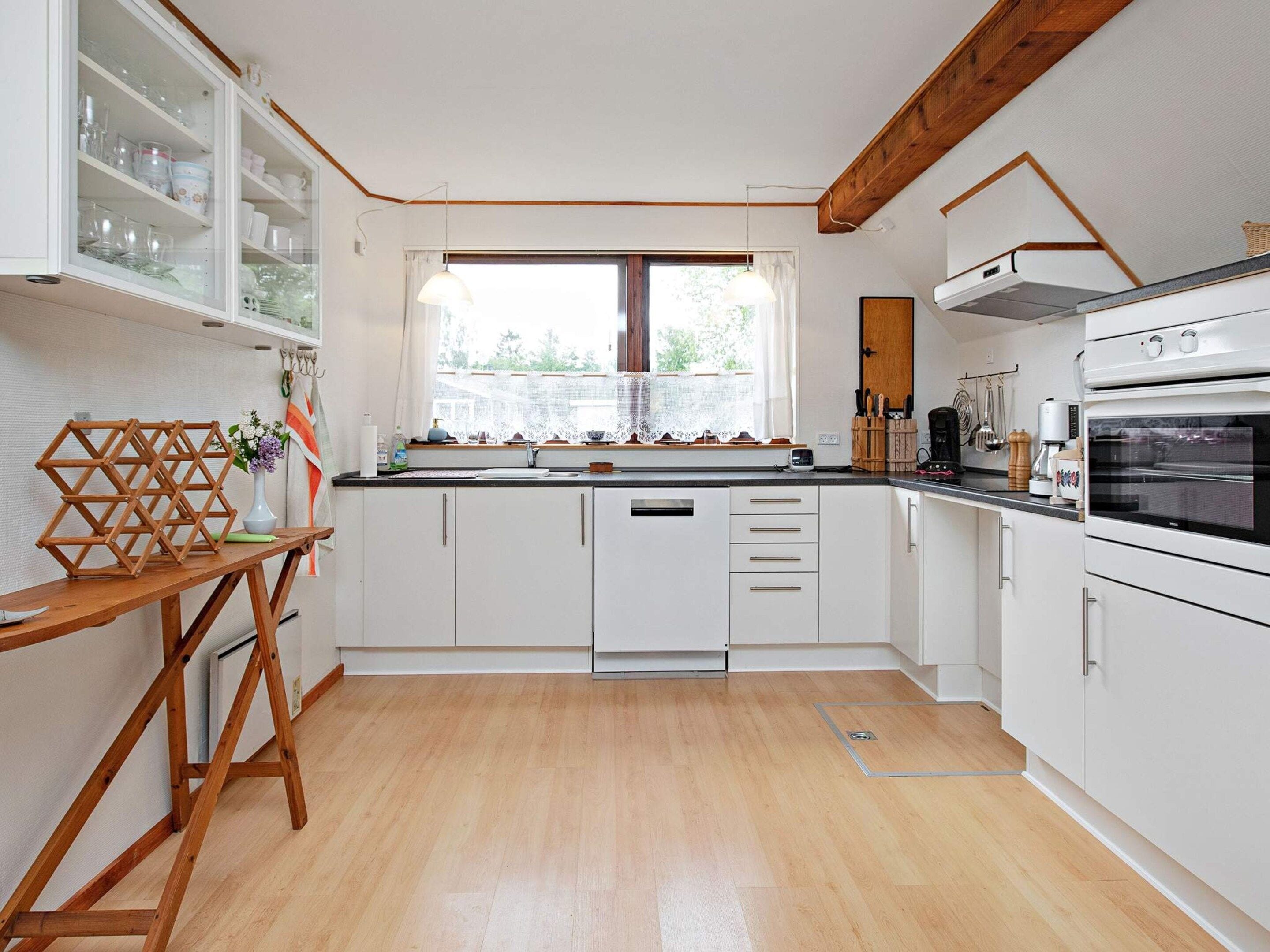 A kitchen with white cabinets, a wooden table, and a window with a view.