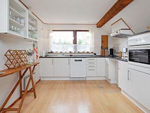 A kitchen with white cabinets, a wooden table, and a window with a view.