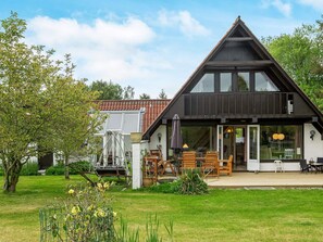 A modern house with a large front porch, a dining area, and a visible staircase leading to the upper floor.