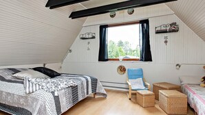 A cozy attic bedroom with a bed, a blue chair, and wicker baskets. - Holiday Home in VÃ¦ggerlÃ¸se (Vaeggerlose)