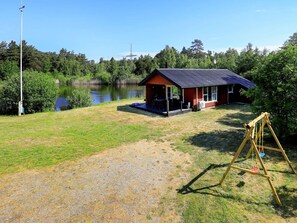 A lodge with a covered patio, a swing set, and a view of a lake.