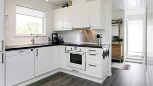 A modern kitchen with white cabinetry, a Bosch dishwasher, a stainless steel range hood, and a black countertop. - 4 Person Holiday Home in Laeso (Læsø)